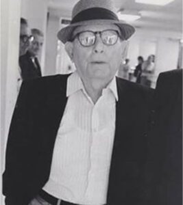 A man in a hat and glasses is standing.