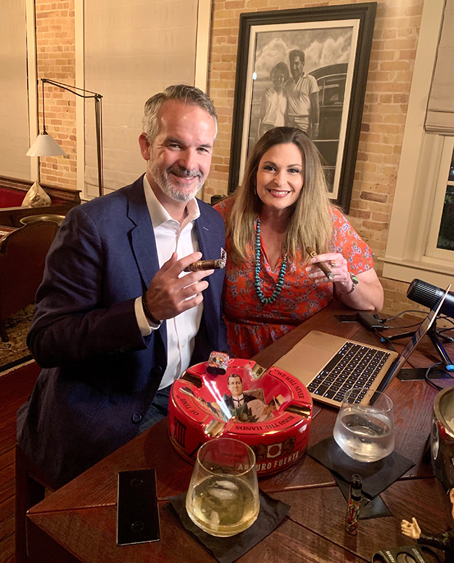 A man and woman sitting at a table with a laptop.