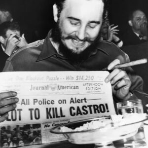Fidel Castro holds up a newspaper headlining the discovery of a plot to kill Castro here, April 23rd. Castro was at the Overseas Press Club at the time.